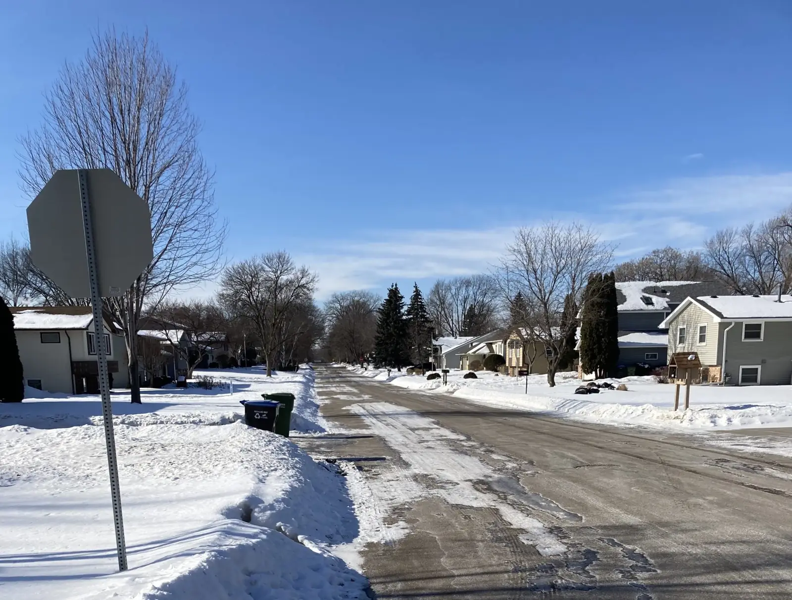 A residential street of houses with snow on the roofs and in the yards